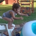 Little Girl Rolls Around Edge Of Inflatable Pool